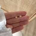Instants Plaisirs – Boucles D'Oreilles Marisa - Plaqué Or, deux petites boucles d'oreilles dorées, portées sur une main